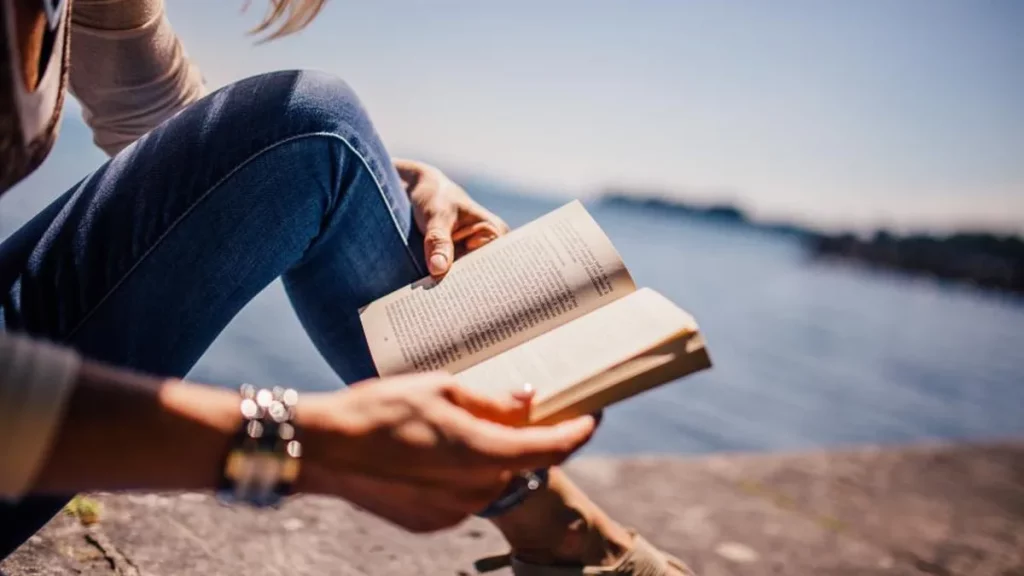 مسافر يقرأ كتابًا على شاطئ بحيرة